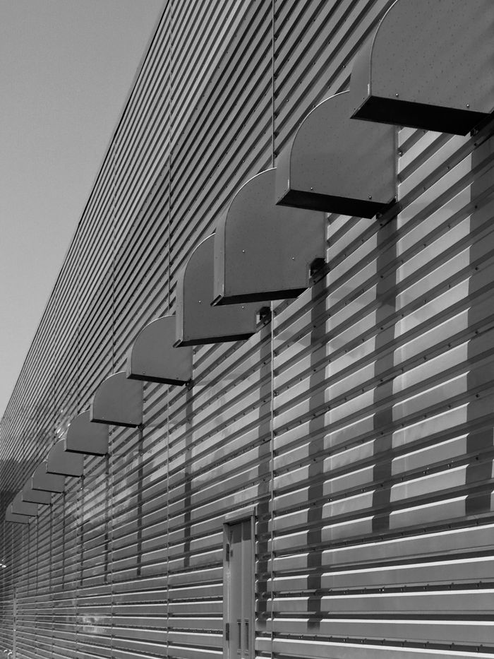 Monochrome image of industrial building facade with geometric lines and shadows.