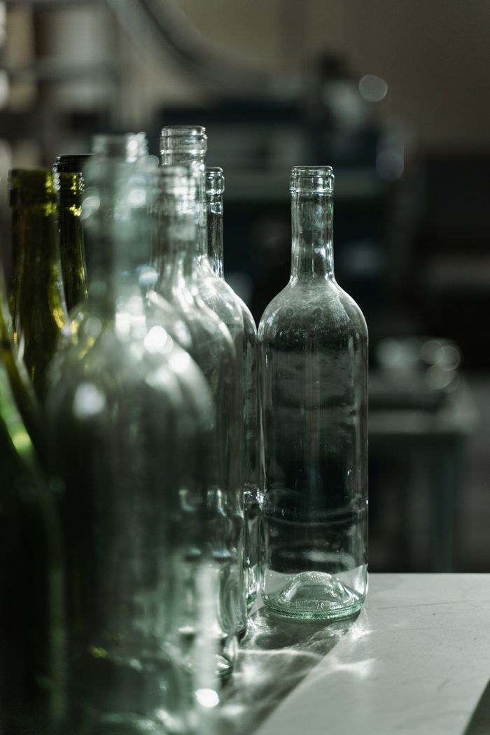 Row of clear glass bottles in a dimly lit industrial environment, highlighting texture and design.