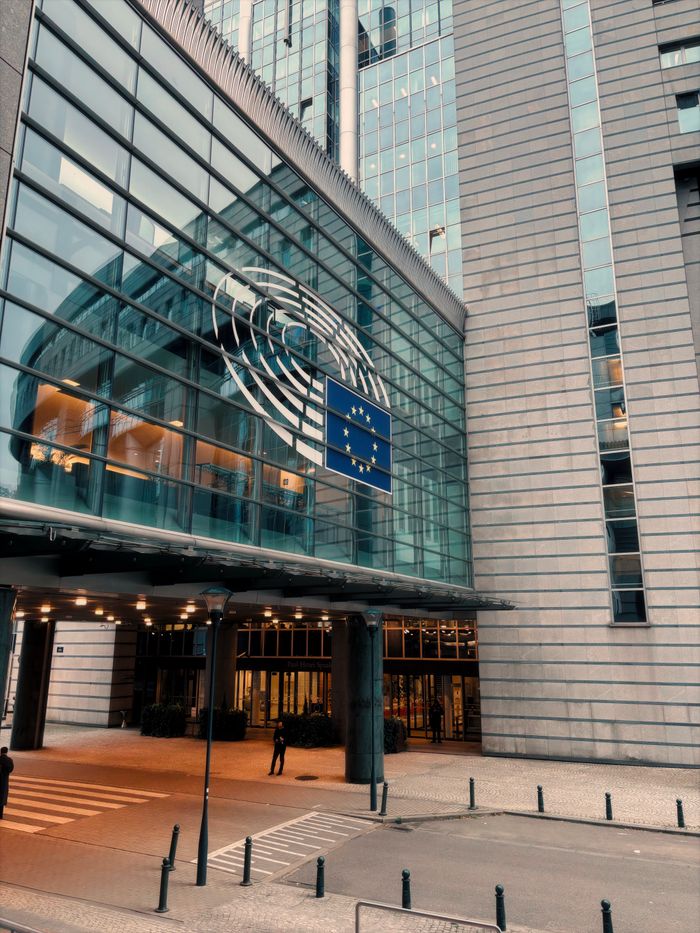 Exterior of the European Parliament in Brussels, showcasing modern architecture and the EU flag.